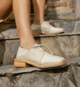 Zapato acordonado de cuero vacuno color marrón oscuro, con suela de goma, horma cuadrada y tacón bajo.