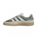 Zapatillas Adidas Handball Spezial ST en tonos gris, verde oliva y blanco. Confeccionadas en gamuza y material textil, con las tres tiras laterales en blanco y suela de goma color caramelo.