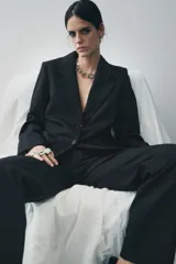 Pantalón negro de tiro bajo con trabillas en la cintura. Cuenta con bolsillos laterales y de vivo en la espalda, detalle de raya planchada en el delantero y cierre frontal con cremallera, botón y gancho metálico.