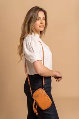 Bandolera compacta de símil cuero color rojo, con correa regulable y desmontable. Posee apertura superior, bolsillo frontal con cierre y bolsillo trasero abierto.