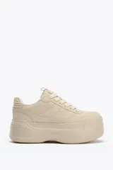Zapatillas deportivas color beige con plataforma alta. Cierre con cordones.