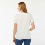 Camiseta blanca de manga corta para maternidad con un pequeño corazón bordado en el pecho.