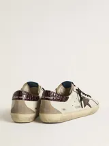 Zapatillas urbanas Golden Goose modelo Super Star, de cuero color blanco con detalles en marrón y beige. Presentan la estrella distintiva de la marca en el lateral, acabado desgastado y suela de goma.