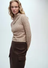 Sweater color beige de tejido de punto, con cuello solapa alto y mangas largas.