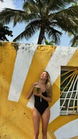 Traje de baño enterizo amarillo con textura arrugada, breteles finos y cierre marrón en el frente.