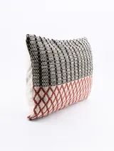 Funda de almohadón rectangular de 30 x 50 cm, con diseño tejido a rayas verticales en blanco y negro en la parte superior, y diseño geométrico de rombos en color ladrillo en la parte inferior.