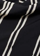 Vestido midi con estampado de rayas verticales blancas sobre fondo negro, cuello perkins, manga corta asimétrica y cierre de cremallera en la espalda. Tejido fluido con acabado satinado y forro interior.