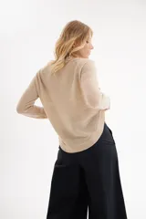 Sweater de punto color beige con cuello redondo y mangas largas con hombros caídos.