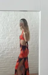 Vestido largo con estampado abstracto en tonos naranja y azul, con escote halter, espalda descubierta y aberturas laterales en la cintura.