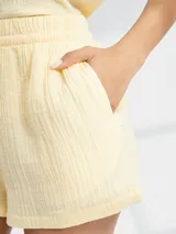 Short de tela color amarillo pastel con cintura elastizada y lazo de ajuste.