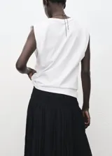 Camiseta blanca de manga corta con hombreras y cuello redondo, de corte recto.