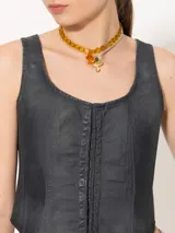 Top estilo corset confeccionado en tejido 100% algodón con proceso de coating simil cuero en tono azulado. Presenta desgastes estratégicos que dejan entrever la base natural, aportando contraste y textura.