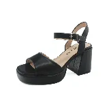 Sandalias negras de cuero sintético con plataforma y tacón bloque. Tira delantera ancha y pulsera al tobillo con hebilla metálica.