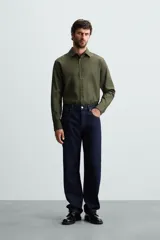 Camisa negra de manga larga con cuello italiano y cierre frontal de botonadura. Presenta un tejido con estructura de fácil cuidado.