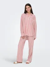 Camisa de manga larga con cuello clásico y cierre frontal de botones. Diseño holgado con bolsillo en el pecho. Estampado de rayas verticales en rojo, blanco y negro.