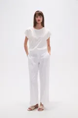 Pantalón blanco de algodón con calce recto y tiro bajo. La tela presenta bordados tipo calado (broderie) a lo largo de toda la prenda.