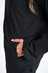 Campera deportiva negra con capucha, cierre frontal y textura microcuadriculada. Presenta puños y ruedo ajustados.