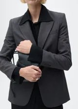 Chaqueta gris con estampado de micro pata de gallo, cuello con solapa, cierre de botón frontal, dos bolsillos delanteros con ribete y solapa, manga larga abotonada y forro interior.