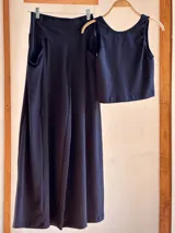 Conjunto negro de lycra de algodón, compuesto por un top corto sin mangas y un pantalón palazzo evasé con bolsillos laterales.