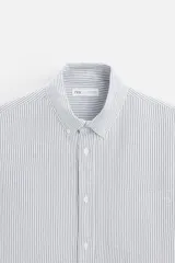 Camisa azul marino de corte regular fit, confeccionada en tejido de algodón Oxford. Tiene cuello abotonado, manga larga con puños abotonados, bolsillo de parche en el pecho y cierre frontal con botones.