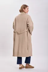 Cardigan largo de punto color beige con cuello solapa, bolsillos laterales y lazo para ajustar en la cintura.