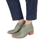 Botines de cuero color oliva con cordones frontales y tacón bloque de madera clara.