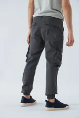 Pantalón cargo gris oscuro, corte slim, con cierre de botón y cremallera, trabillas para cinturón, bolsillos cargo con botón y puños ajustados.