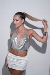 Top corto plateado con lentejuelas metálicas y cadenas finas en cuello y espalda.