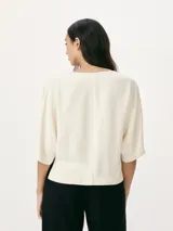 Blusa color crema con escote en V y mangas cortas amplias.
