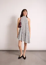 Vestido corto negro con cuello halter y falda con vuelo asimétrico.