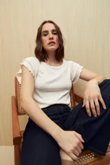 Top color rosado de tejido de punto acanalado, con cuello redondo y mangas cortas con volados.