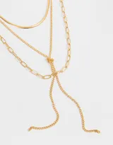 Collar corto dorado de tres capas con diferentes tipos de cadenas y nudo decorativo.