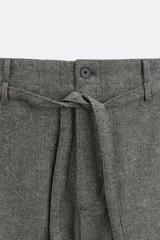 Pantalón gris de corte recto con cinturón de la misma tela, bolsillos laterales y traseros de vivo.