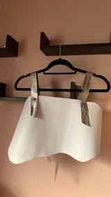 Top corto de ecocuero negro con corte asimétrico y un tirante ancho de ecocuero blanco con textura de piel de cocodrilo. Se ajusta con botones o lazo en la espalda.