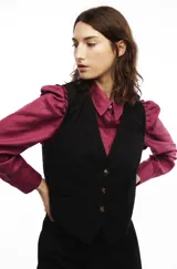 Chaleco negro de sastrería con calce entallado y hebilla para ajustar en la cintura.