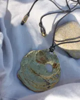 Collar con dije grande de bronce con forma de ostra y cordón de algodón ajustable color gris.