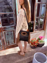 Cartera bandolera negra de cuero con forro interno de tela, detalle de flecos de cuero marrón en la parte inferior y asa larga regulable.