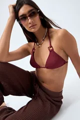 Top de bikini negro confeccionado en tejido con textura, de diseño triangular y detalle de aros cuadrados en los breteles. Se ajusta en cuello y espalda con lazos finos.