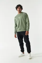 Buzo verde oliva de felpa con cuello redondo, puños y cintura acanalados. Estampado frontal con la frase "The Real Balance" en letras blancas y logo de la marca Mistral.