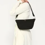 Bandolera Guess modelo Mauve, color negro, con correa ajustable, cierre superior y logo triangular dorado en el frente.