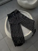Pantalón de jean negro con tachas plateadas en forma de corazón.