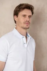 Chomba azul con cuello clásico, tapeta de dos botones y logo bordado en el pecho.