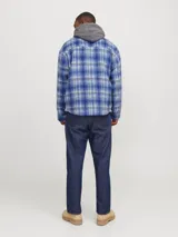 Sobrecamisa corta de manga larga con cuello sport y fit cómodo, confeccionada en tejido plano con efecto lana a cuadros azules y grises. Cuenta con cierre frontal de cremallera, puños con botones, solapa cortaviento, bolsillos en pecho y delanteros.