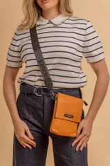 Bandolera tipo phone bag pequeña, color marrón claro, con correa de galón regulable. Tiene un compartimento principal y un bolsillo adicional con tapa.