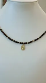Collar de cristales checos color marrón oscuro con detalles dorados y medalla dorada de la Virgen María.
