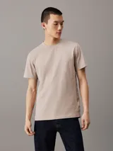 Remera color beige de algodón, con cuello redondo y mangas cortas. Cinta lateral con logo de la marca.