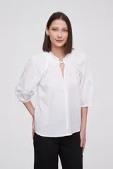 Blusa blanca de algodón con escote en V con lazos, mangas 3/4 abullonadas y corte holgado.