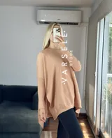 Maxisweater color crudo, de tejido símil bremer, talle único (abarca hasta 2xl). Presenta detalles en las mangas, aperturas laterales y es más largo en la parte trasera.