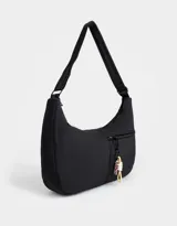 Cartera saca negra de tela deportiva con correa regulable, cierre superior y bolsillo frontal con cierre. Incluye charm lateral.