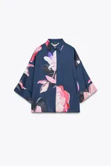 Camisa azul con estampado de flores rosas, cuello solapa y manga corta.